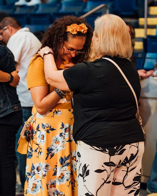 photo of an older woman praying for an emotional younger woman in a church setting