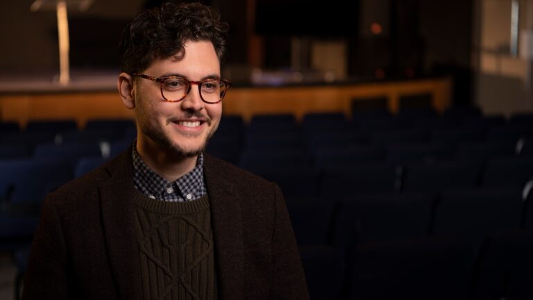A man with glasses smiles