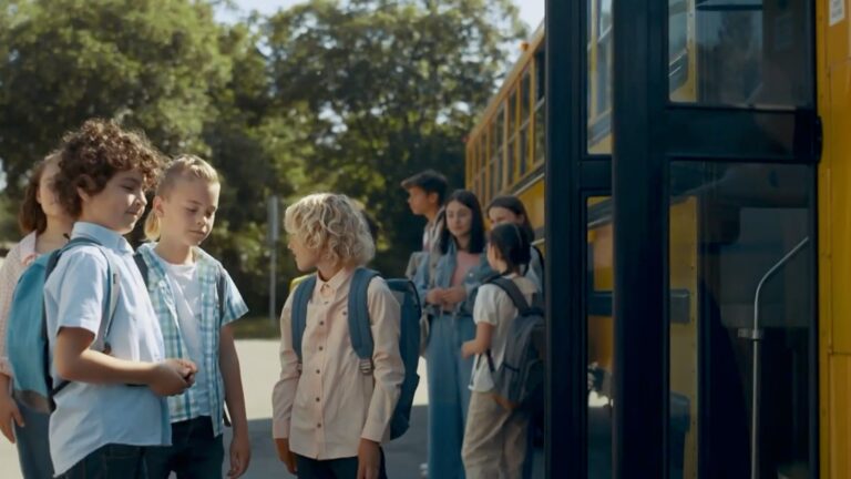 Children stand next to a school bus
