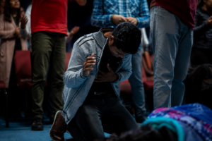 Man praying on his knees in a crowd