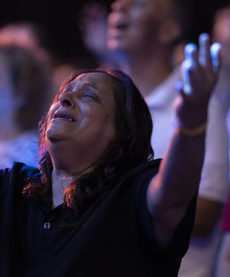 Woman worshipping with light purple lighting indoors