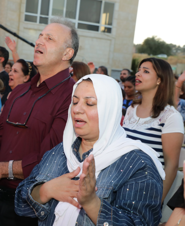 Arabic woman worshipping at Jordan event